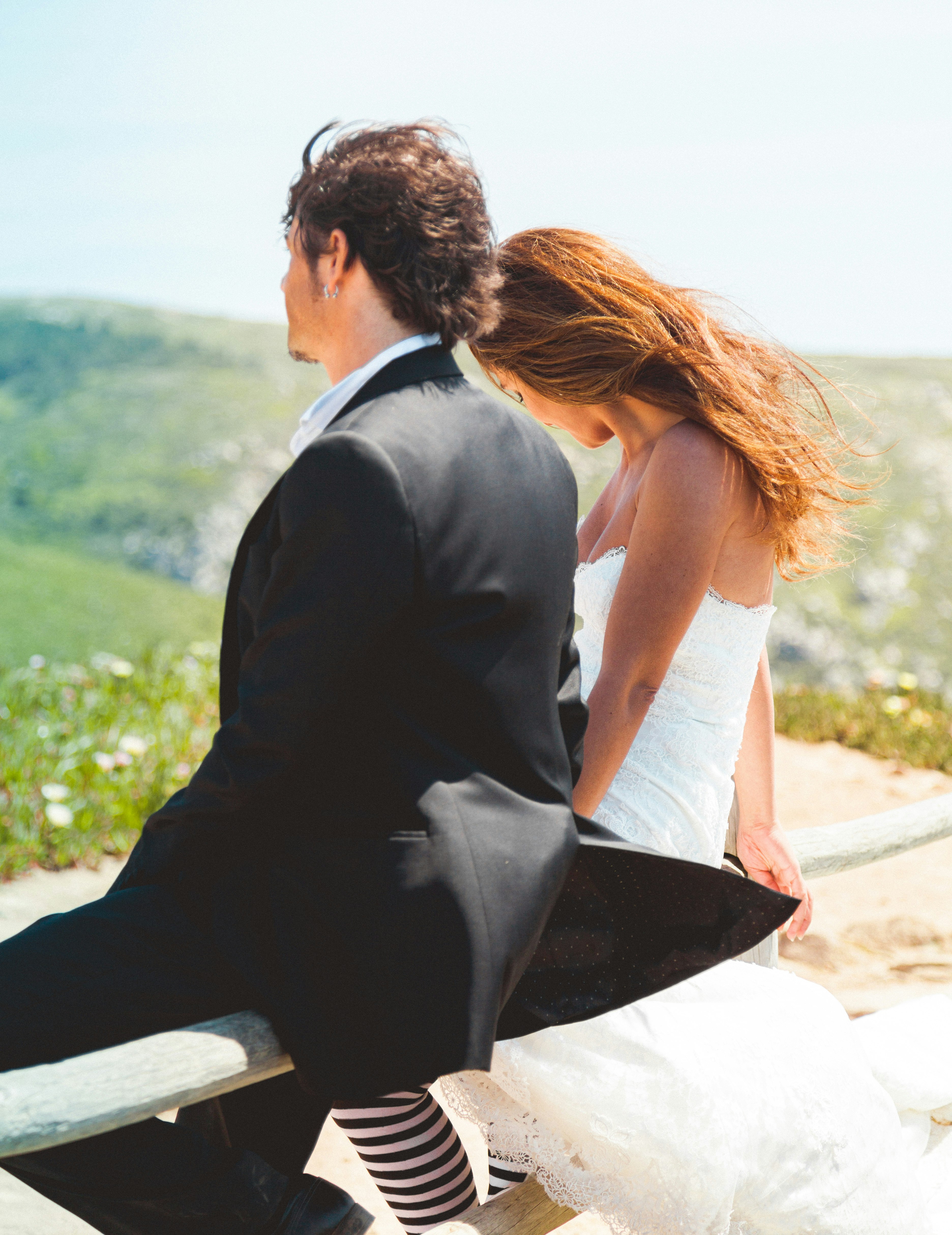 man and woman sitting on white sand during daytime